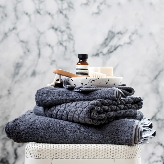 dark gray bamboo bath towels with brush essential oil and a soap on the top