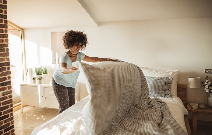 young woman making bed