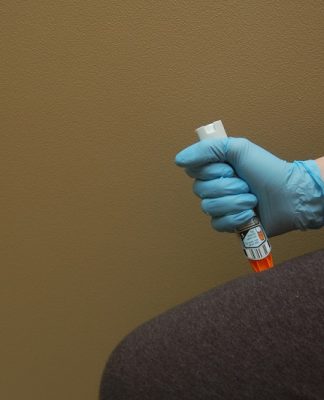 picture of a person using epipen standing in front a brown wall