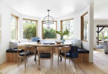 circle wooden dining table surrounded with stools and view on mountains