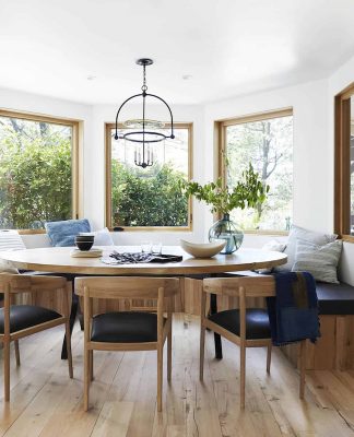 circle wooden dining table surrounded with stools and view on mountains