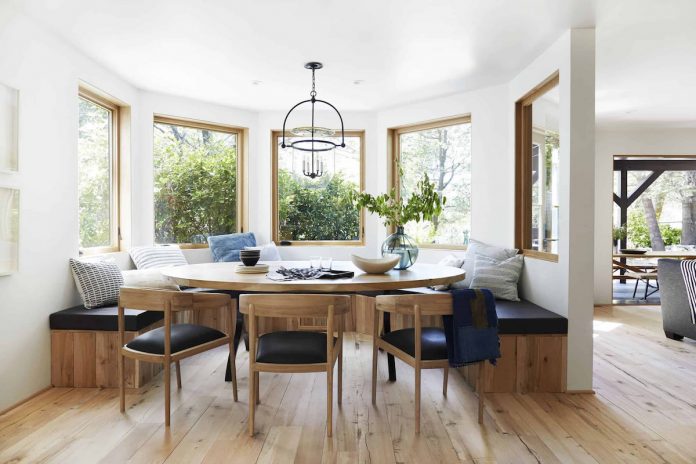 circle wooden dining table surrounded with stools and view on mountains