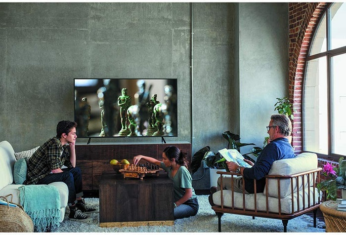 picture of persons in a living room in front a big smart tv 75 inches 