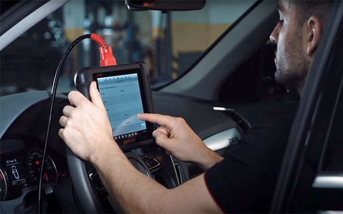 Man working on car diagnostic tool while sitting in the car
