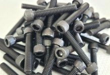 Assorted black button head screws arranged on a white surface.