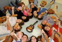many children laying on a floor holding on an ukulele