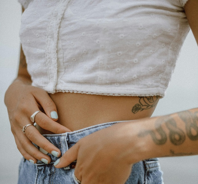 close up of a woman in a white crop top and jeans